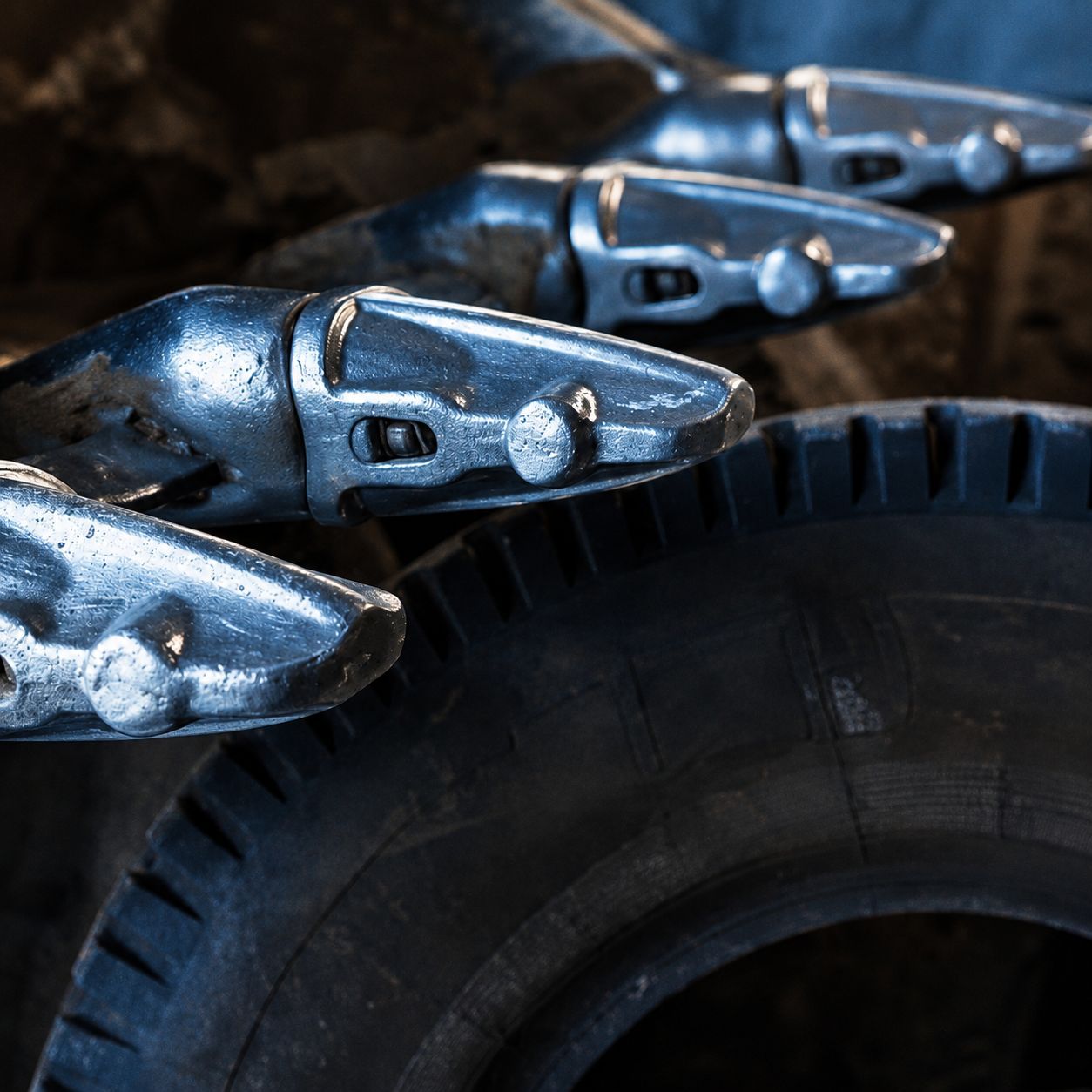 Silver robotic snake coils over a dark tire tread, close-up