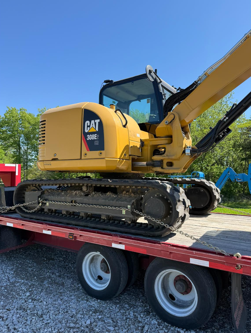 Yellow excavator working on a dirt mound at a construction site under a clear sky