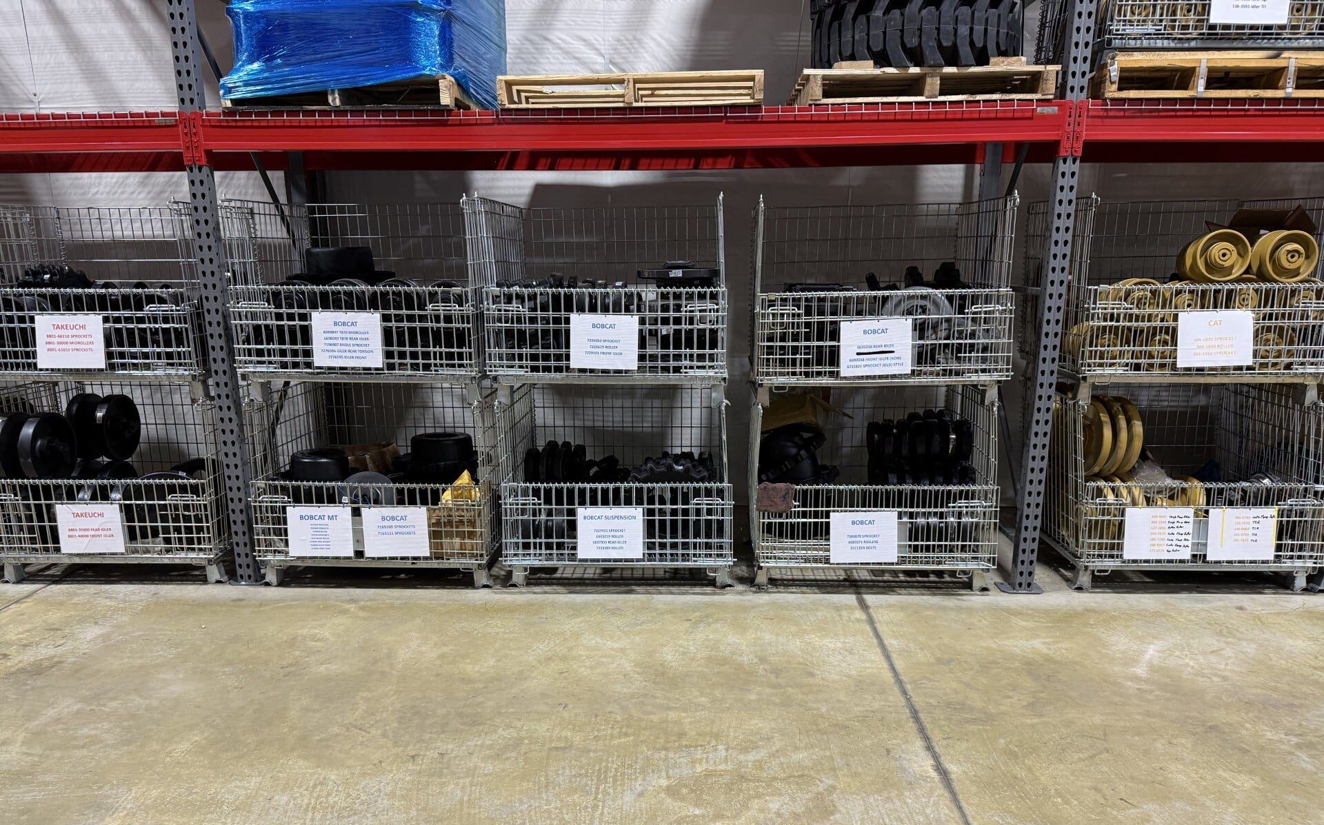 Warehouse shelves stacked with metal wire bins of parts and rolled materials, labeled and organized.