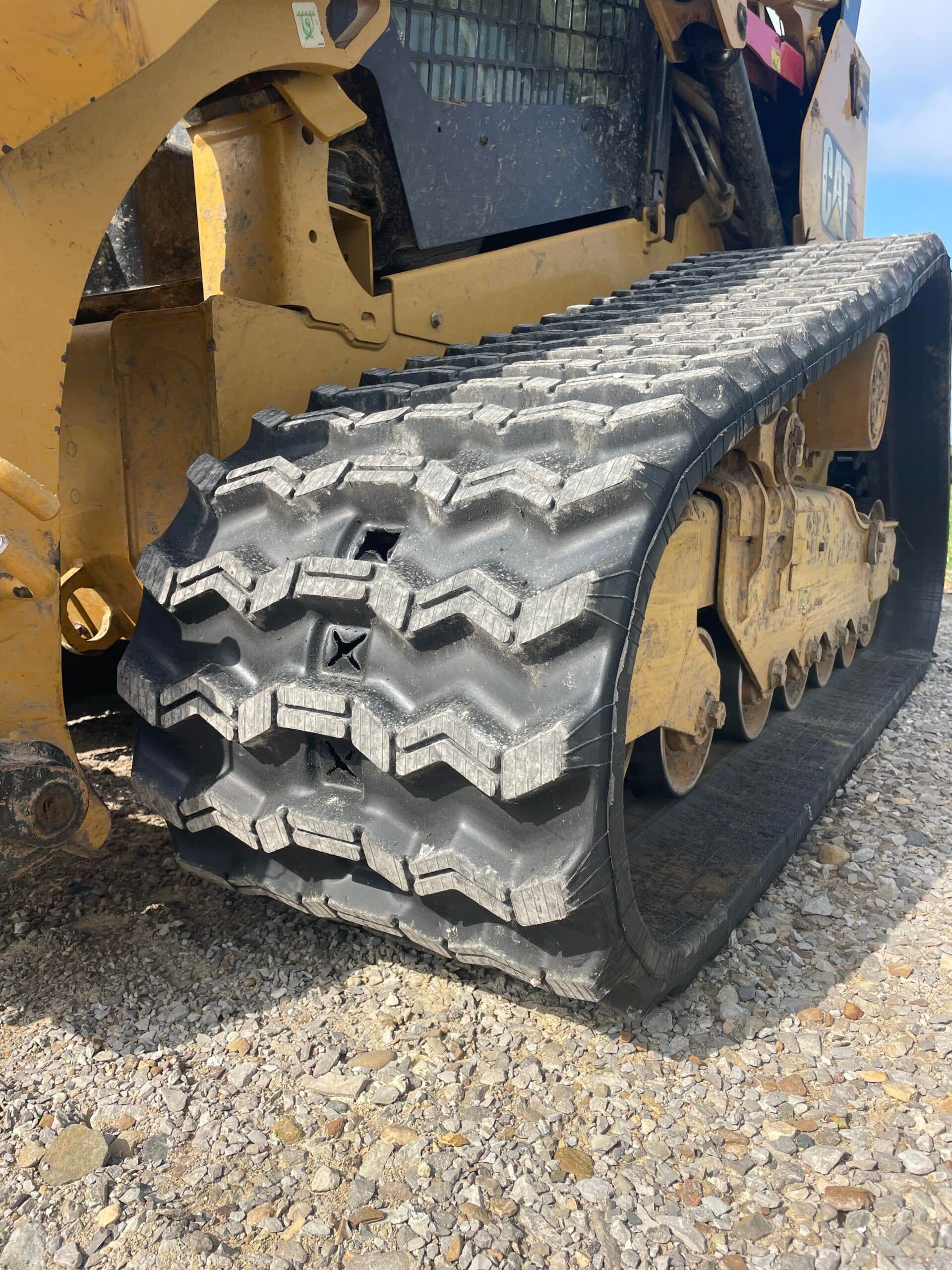 Close-up of a yellow tracked bulldozer’s tread on gravel.