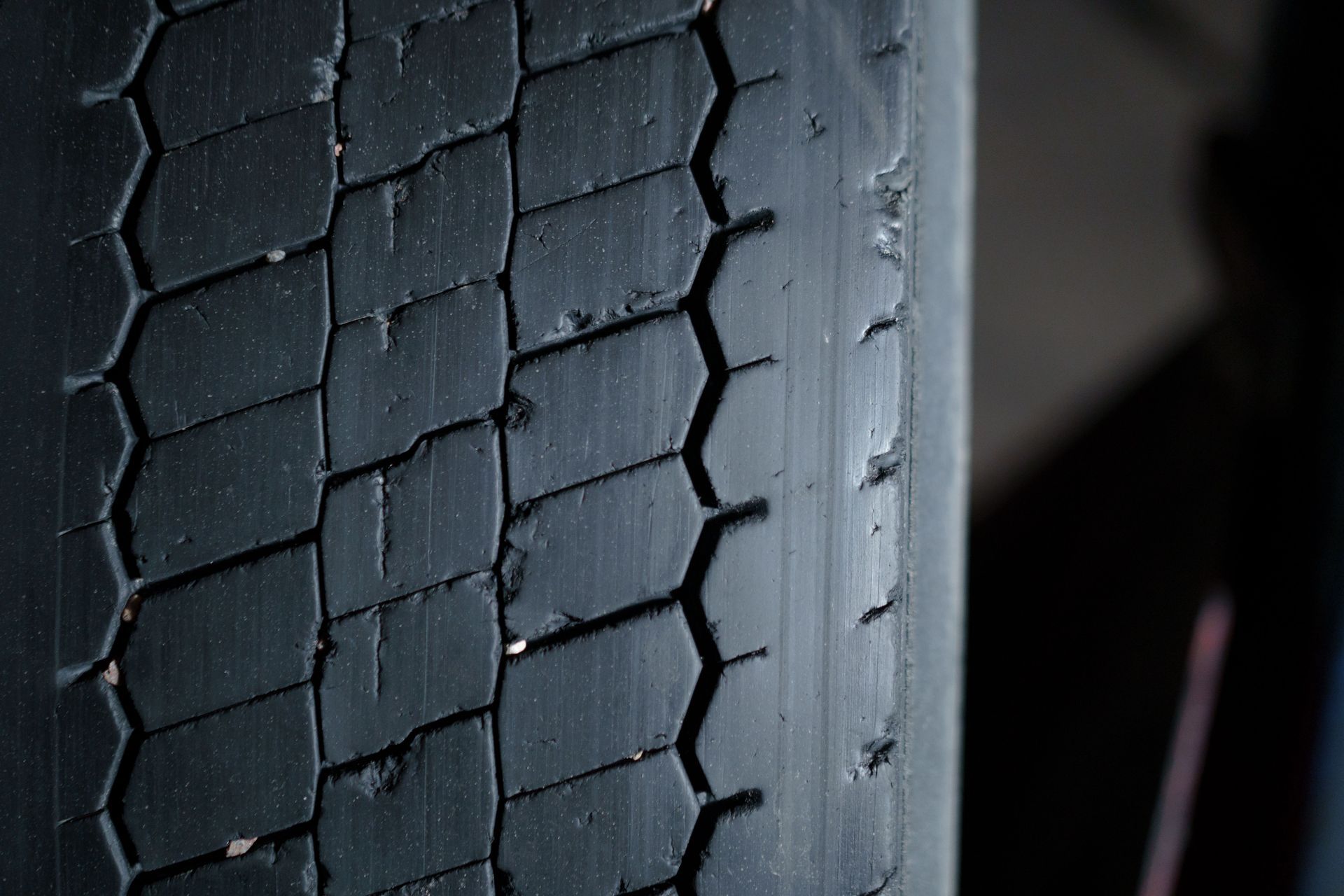 Close-up of a worn black tire tread with visible cracks and grooves