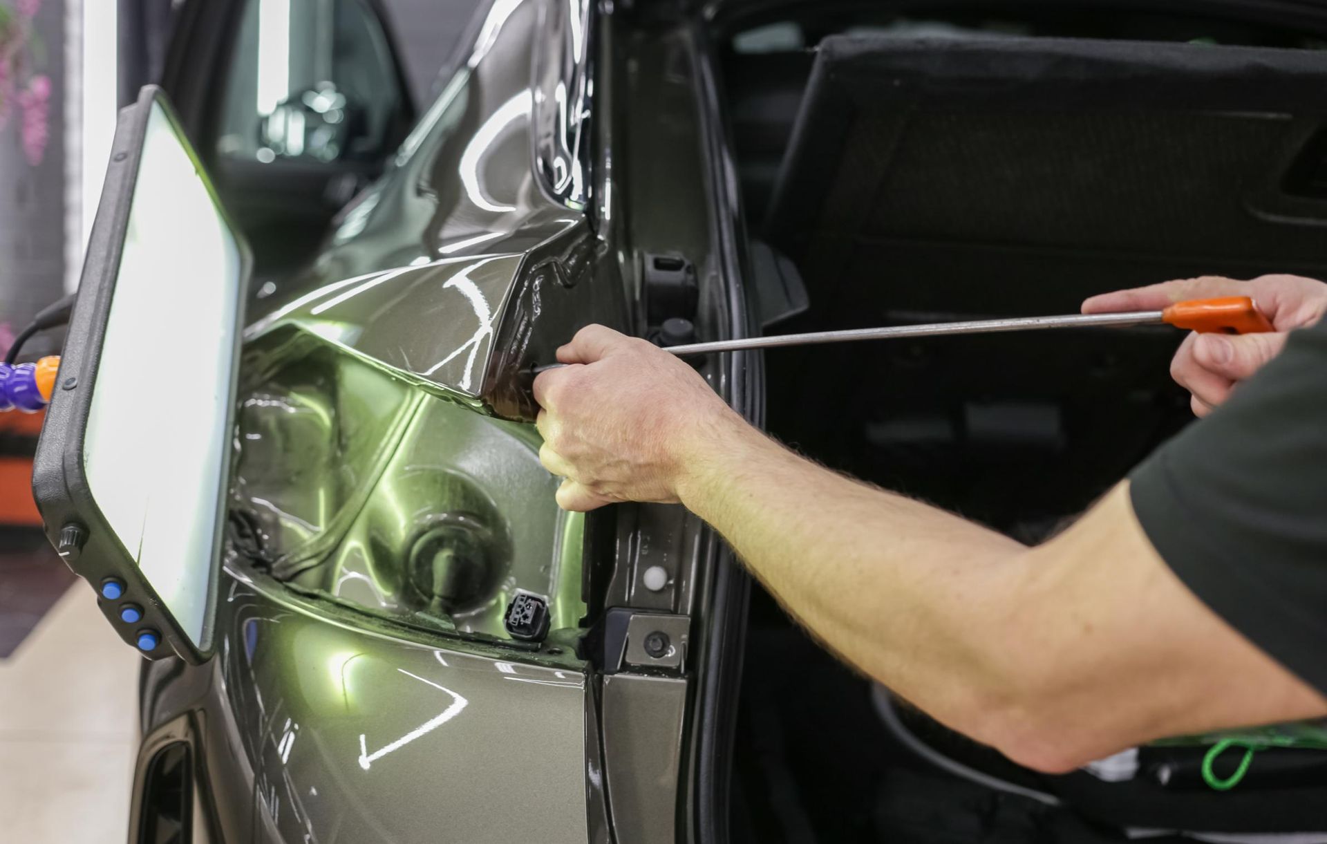Person using a tool to repair a dent on a car's body.