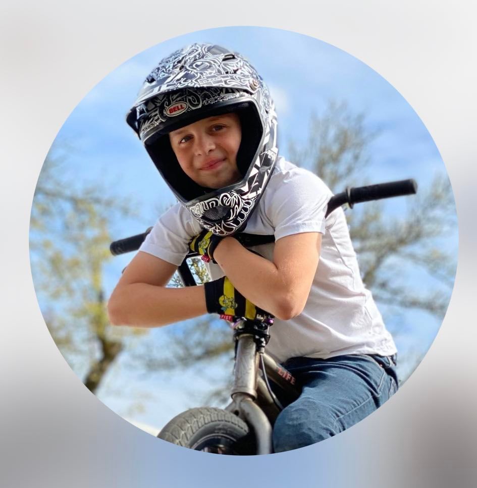 A young boy wearing a helmet and gloves is riding a bike.