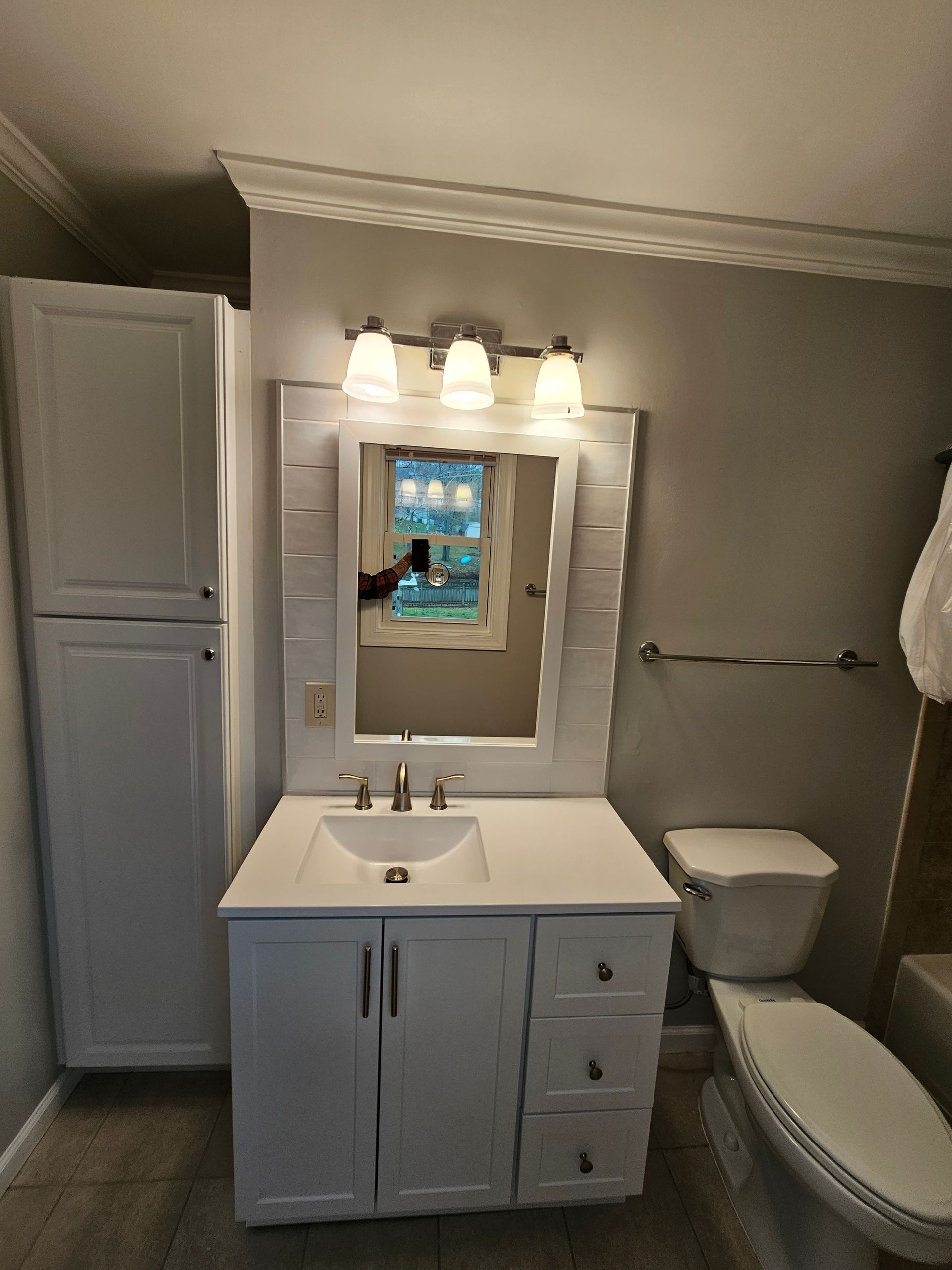 Small bathroom with white vanity, mirror lights, toilet, and shower curtain.