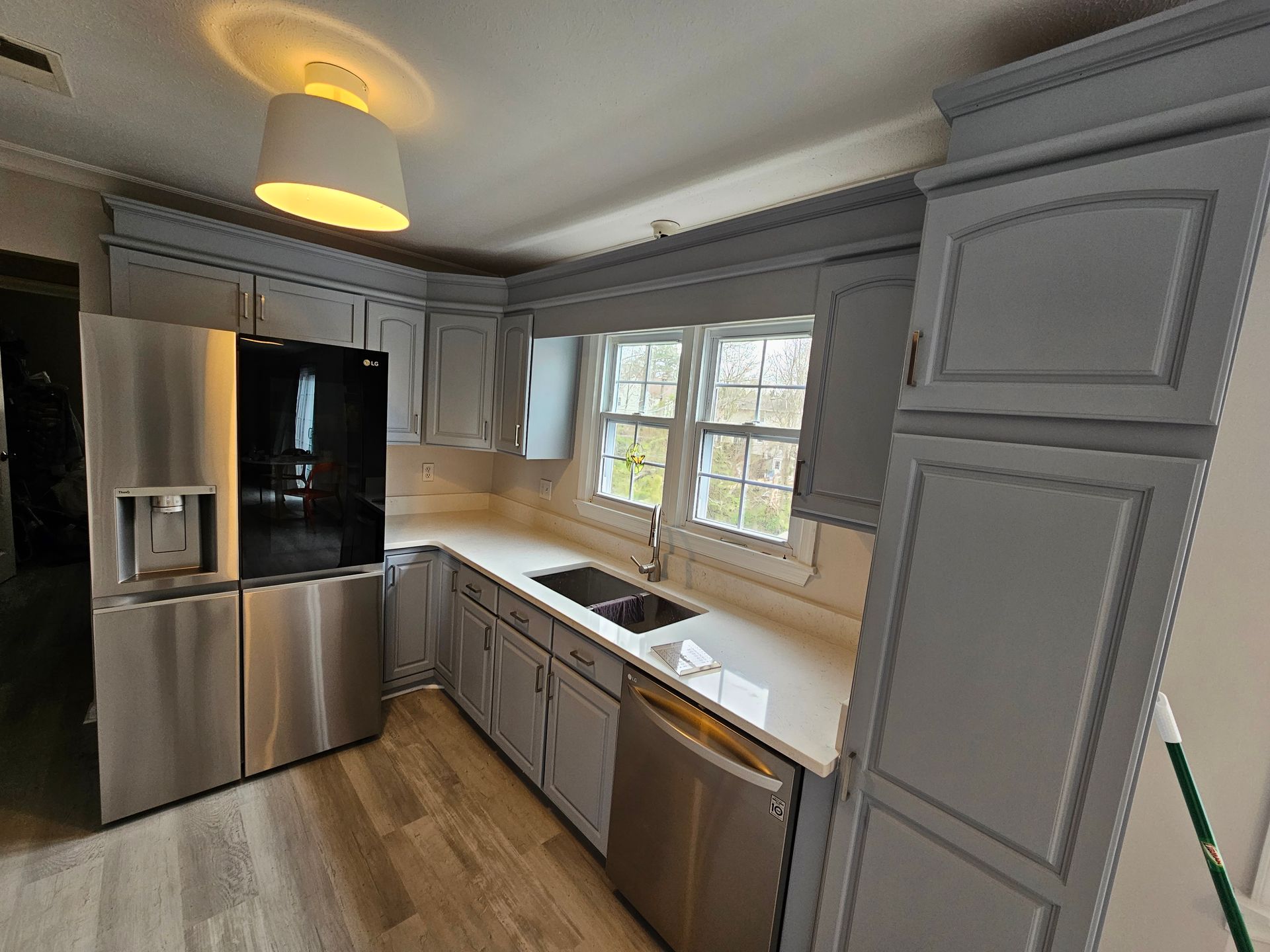 Modern kitchen with gray cabinets, stainless steel appliances, wood floor, and large window over the sink