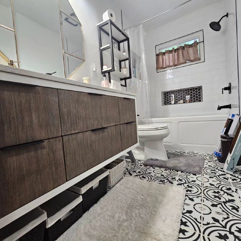 Modern bathroom with patterned tile floor, vanity, toilet, and shower wall shelf.