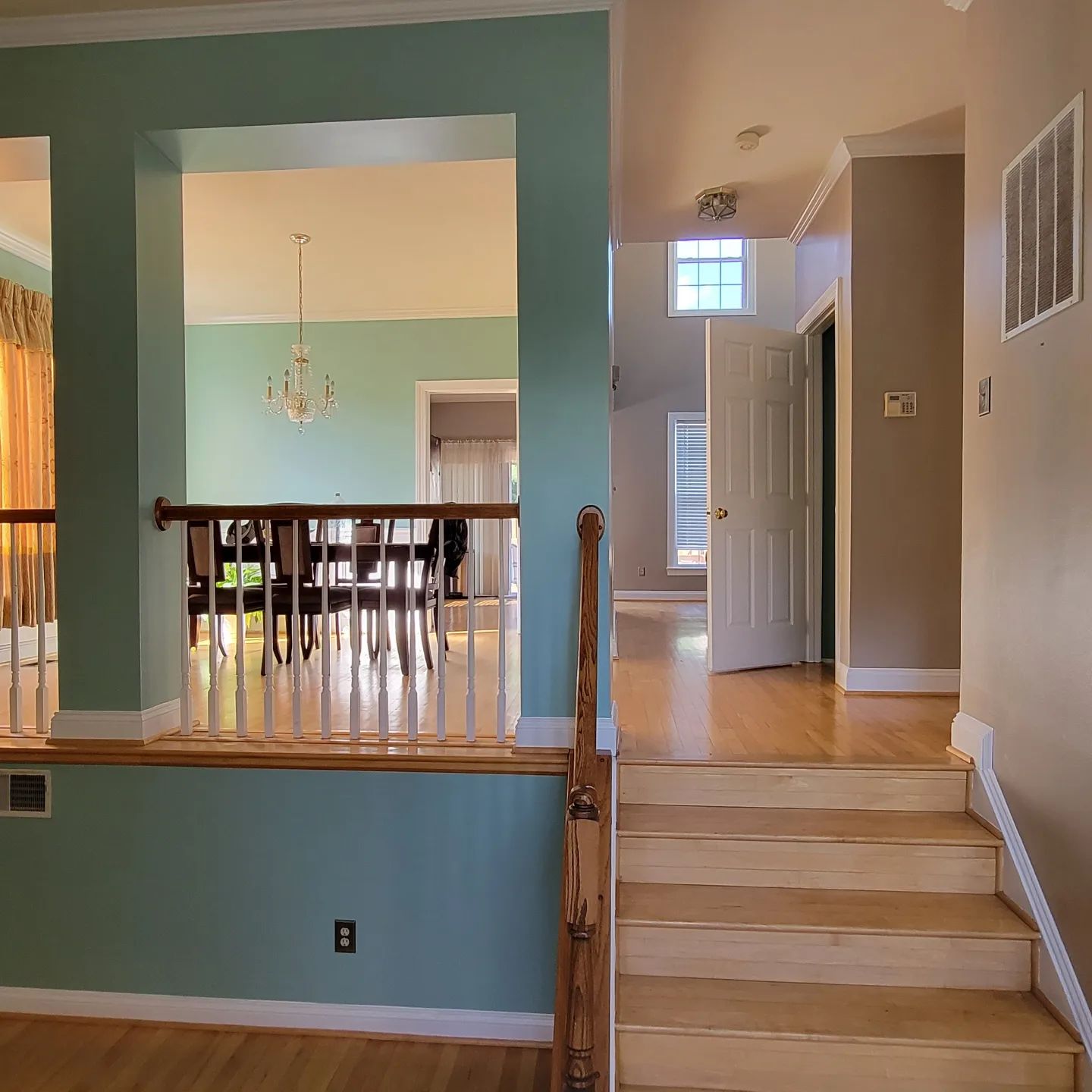 Open-concept home interior with teal walls, staircase, and dining area visible through a large opening