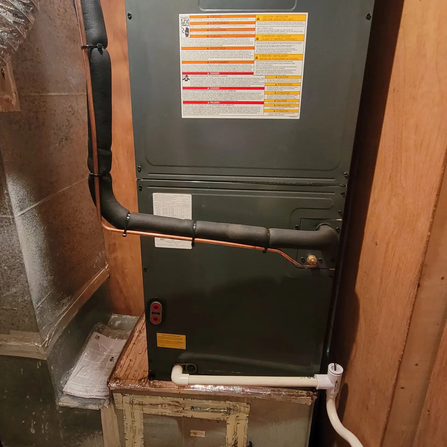 Green HVAC furnace with black and white pipes in a small utility closet