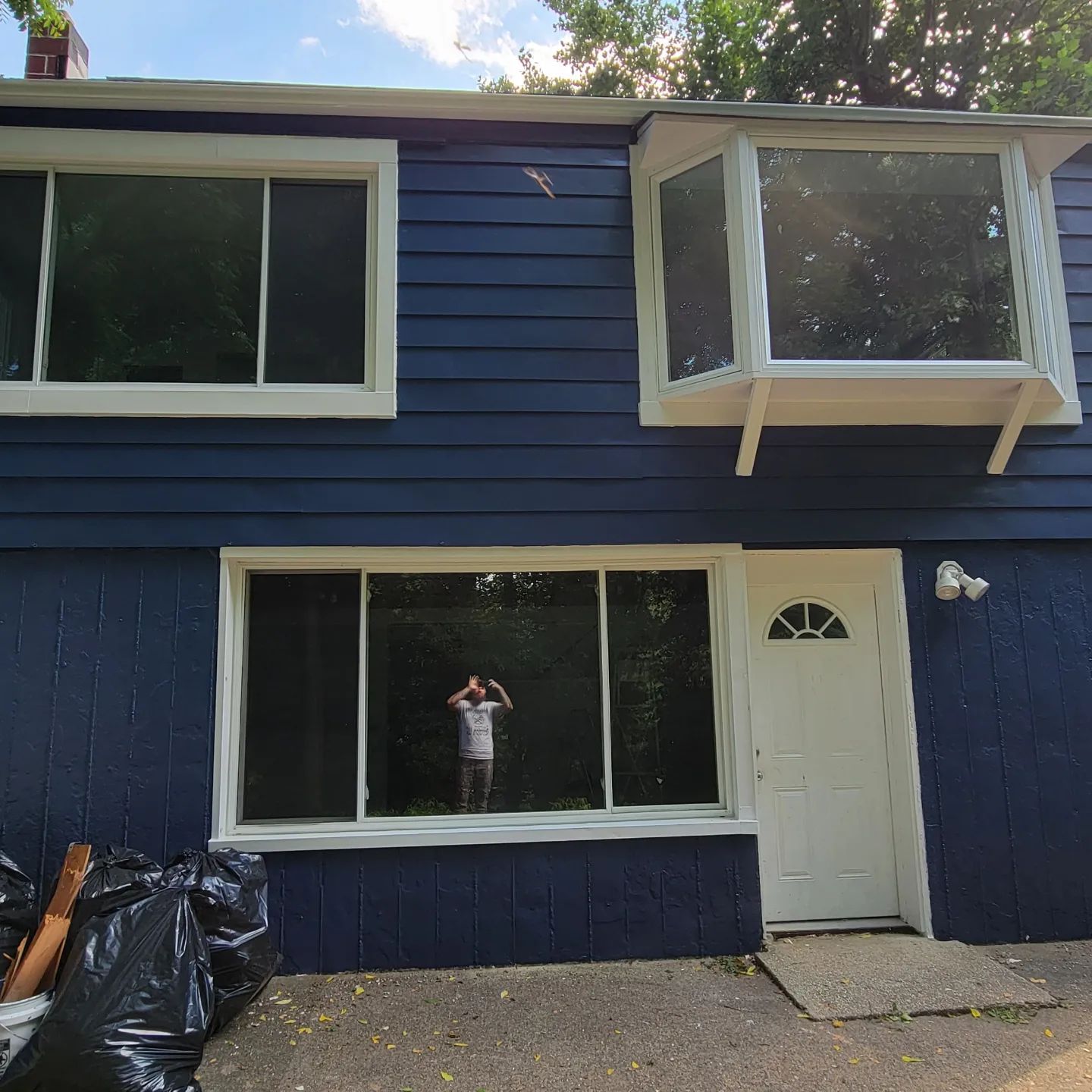 Blue two-story house exterior with white trim, large windows, and a white front door.