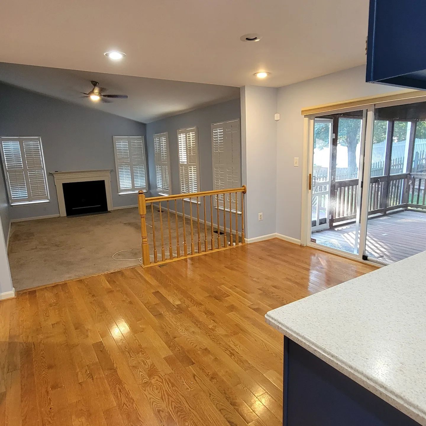 Empty open-plan living room with hardwood floors, gray walls, and sliding glass doors to a deck.