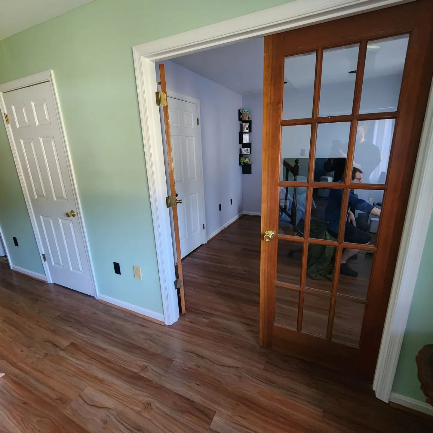 Open French doors to a hallway with white walls and wood floors in a home
