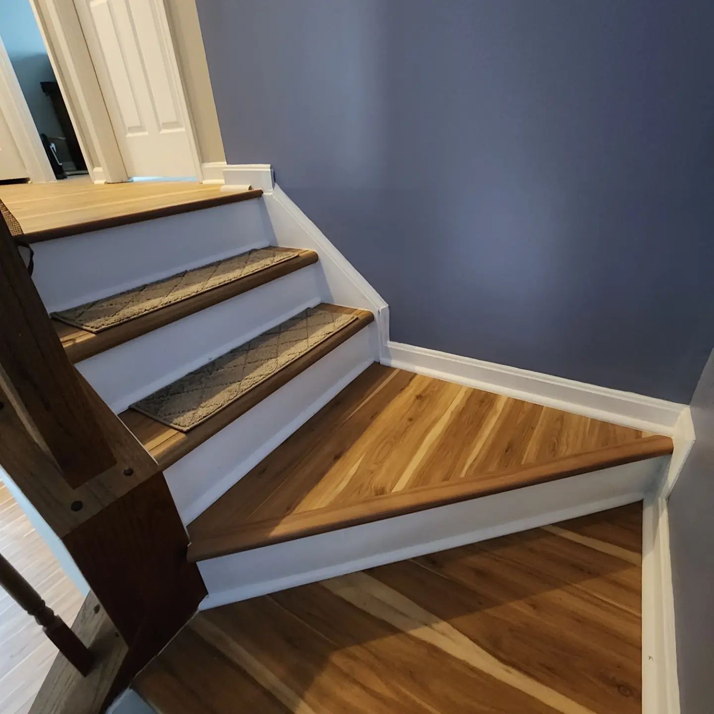 Indoor staircase with carpeted steps, wood landing, and blue wall