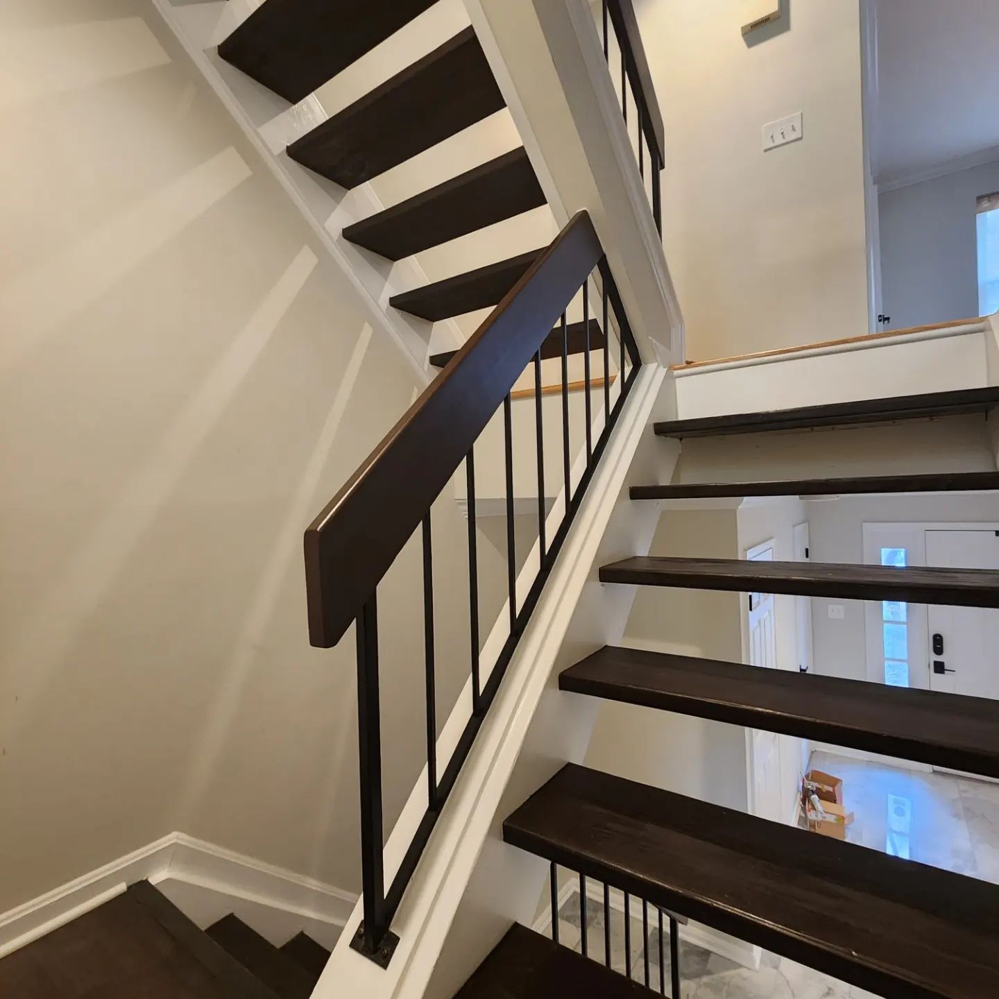 Interior staircase with dark wood steps, black railing, and beige walls in a modern home