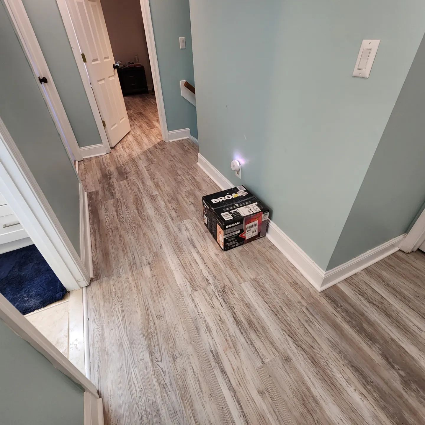 Hallway with light wood flooring and a small box emitting smoke on the floor