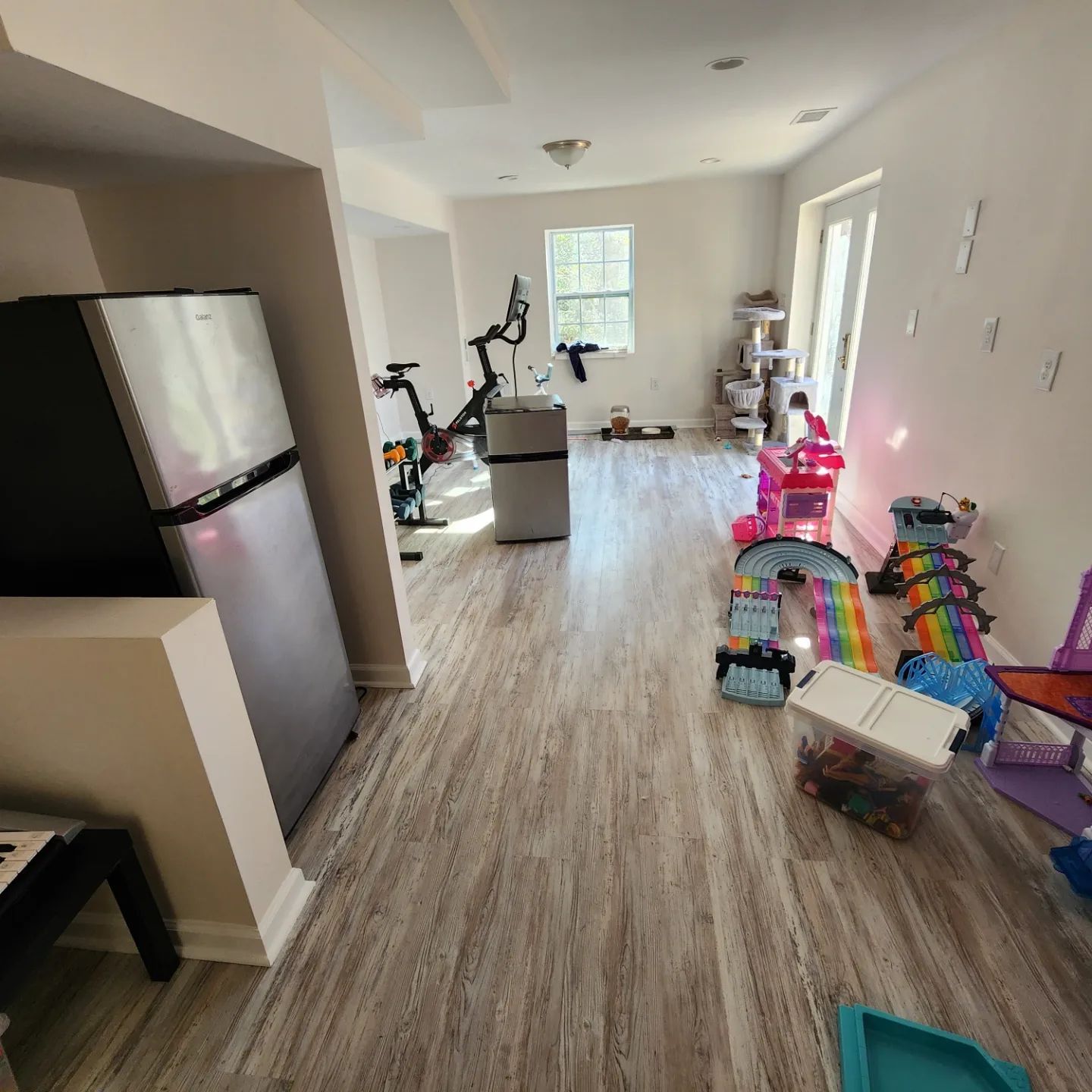 Long kitchen with exercise bike, storage boxes, and toys along the right wall.