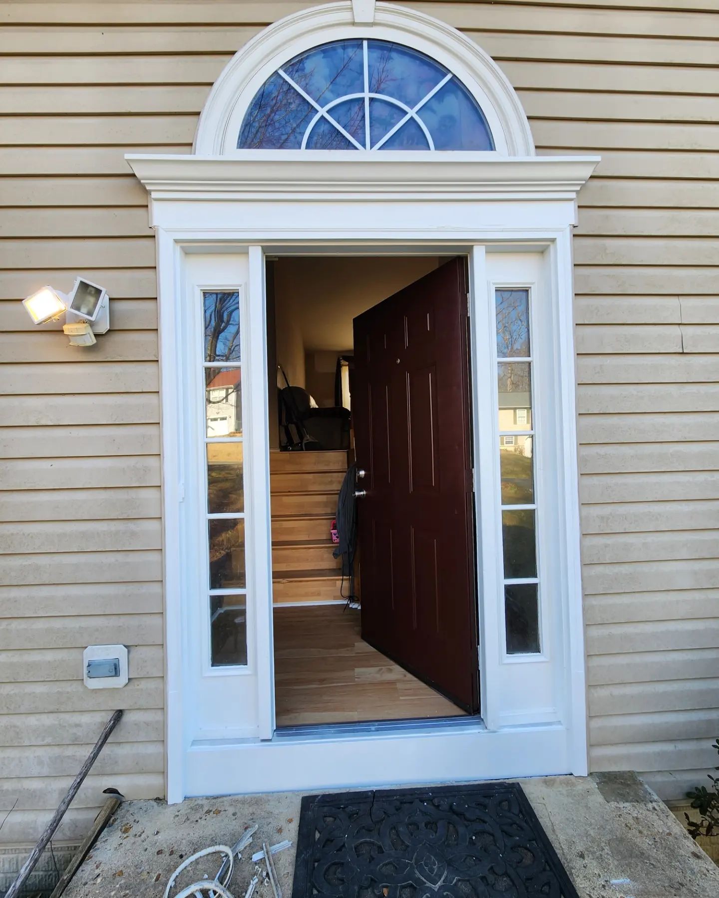 Open front door with white trim and arched window above, leading into a house entryway.