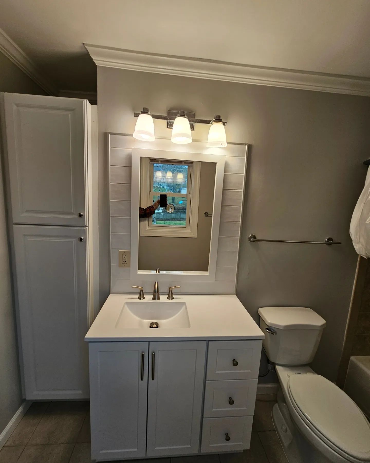 Bathroom with white vanity, mirror, lights, toilet, and bathtub in gray walls