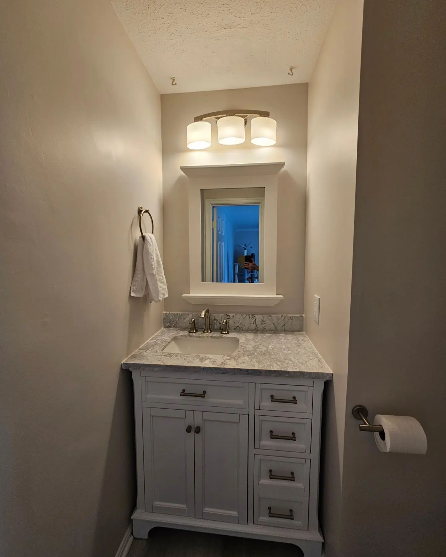 Narrow bathroom with white vanity, granite countertop, mirror, and overhead lights