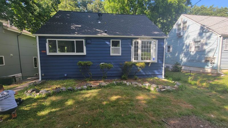 Small blue house with white trim and a front lawn, viewed from the street.