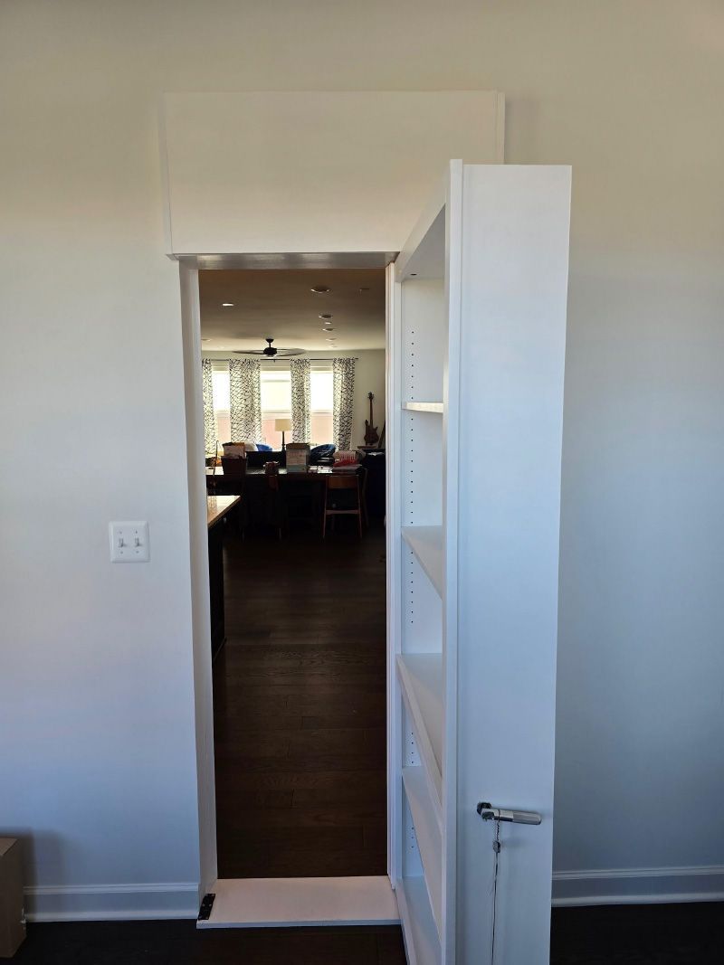 Open doorway to a dimly lit dining room, with a white shelving unit in the foreground.