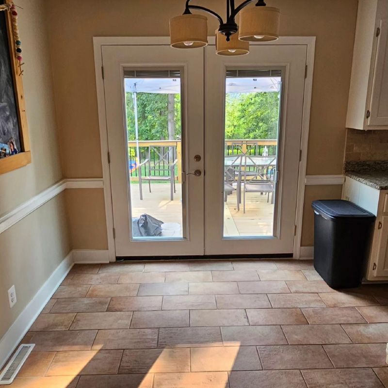Kitchen with tiled floor, French doors to a deck, and sunlight streaming in.