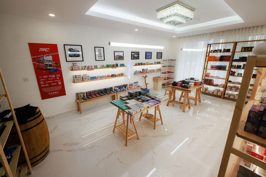 Bright art studio with paintings, shelves, and tables displaying craft supplies under a ceiling light