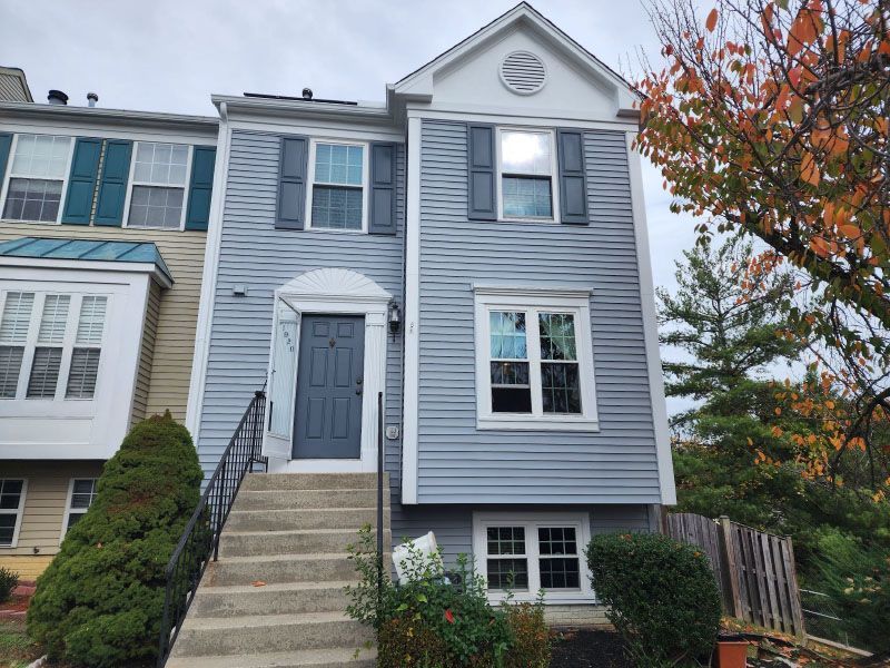 Gray townhouse with front steps, white trim, and autumn trees