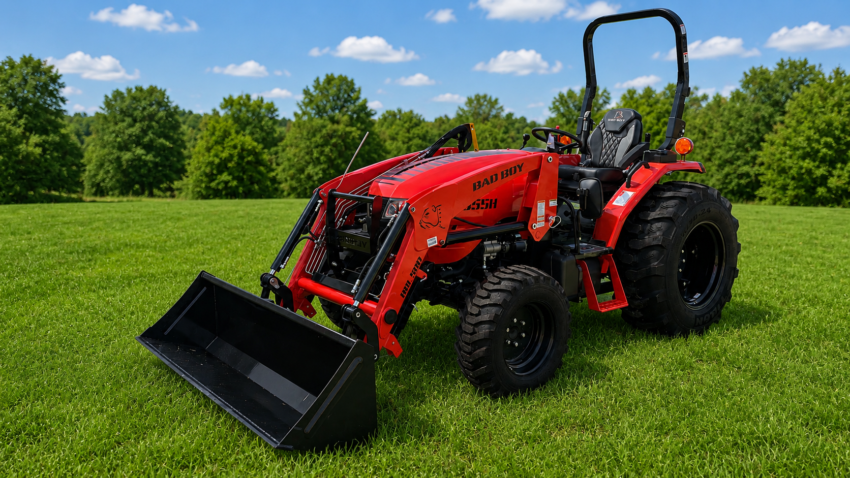 Red tractor with front loader on green grass under a blue sky