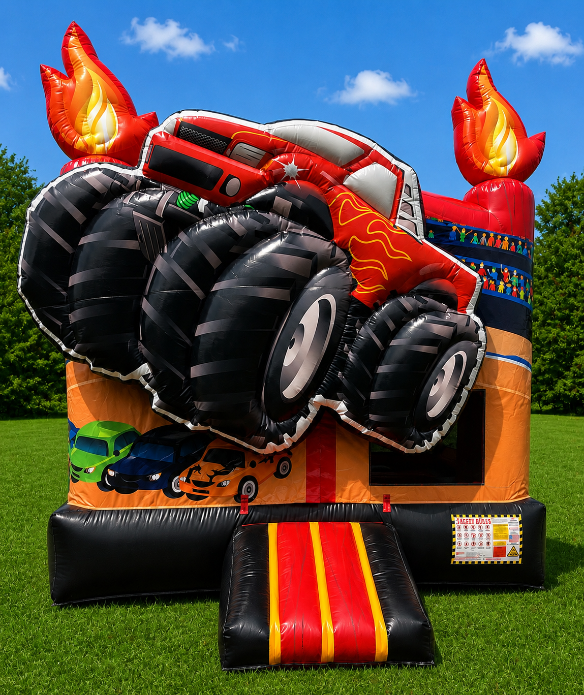 Red monster truck bounce house with flame graphics and a black-and-red inflatable slide on grass.