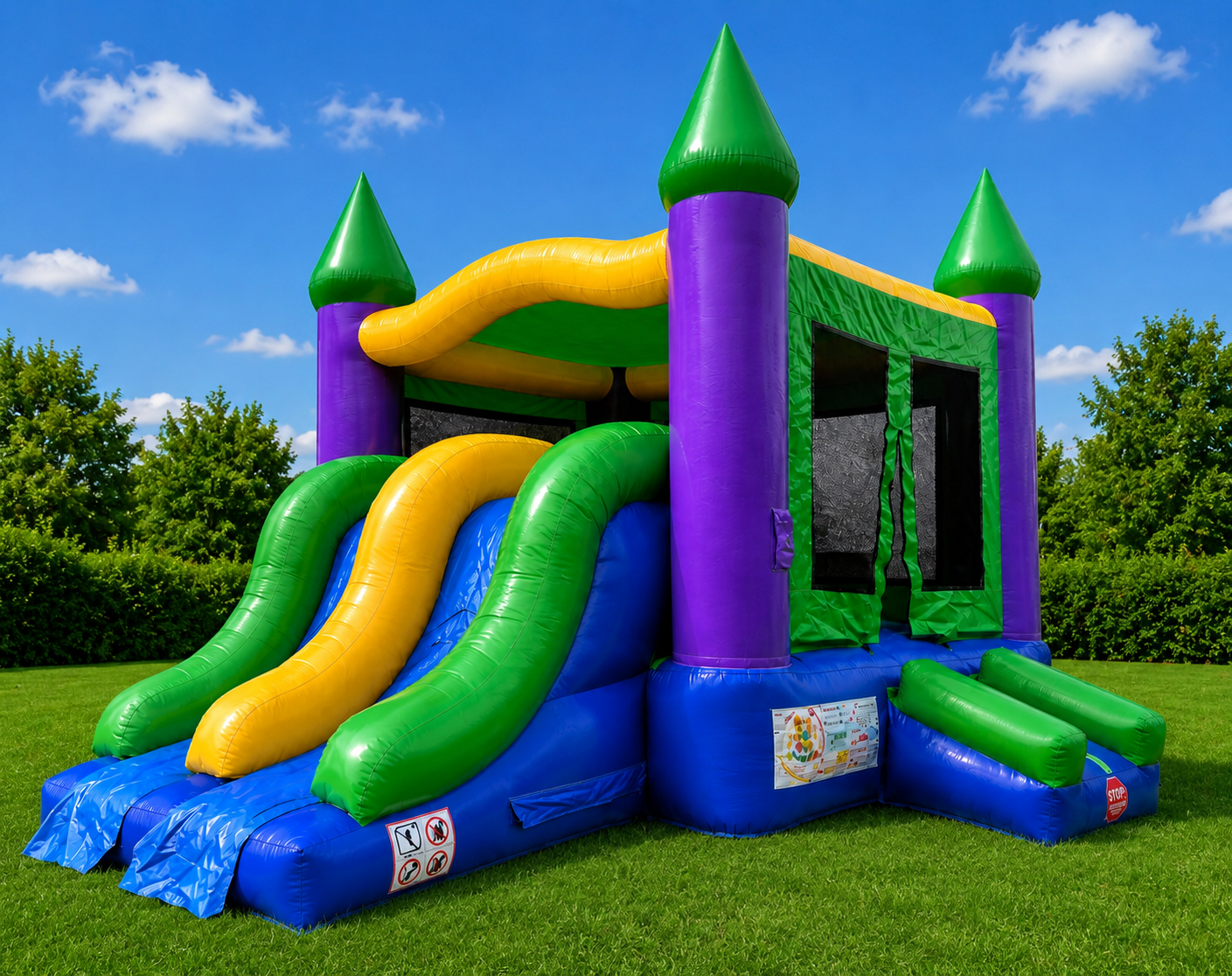 Colorful inflatable bounce house with slides on a grassy lawn under a blue sky