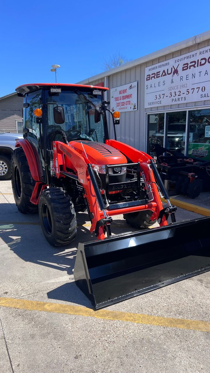 Black utility side-by-side ATV in a shop, shown in profile with orange equipment nearby.