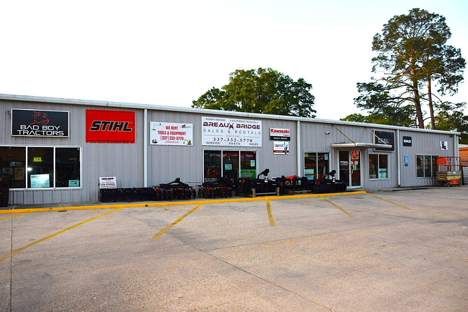 Small storefront auto parts shop with STIHL sign, gray exterior, and empty parking lot