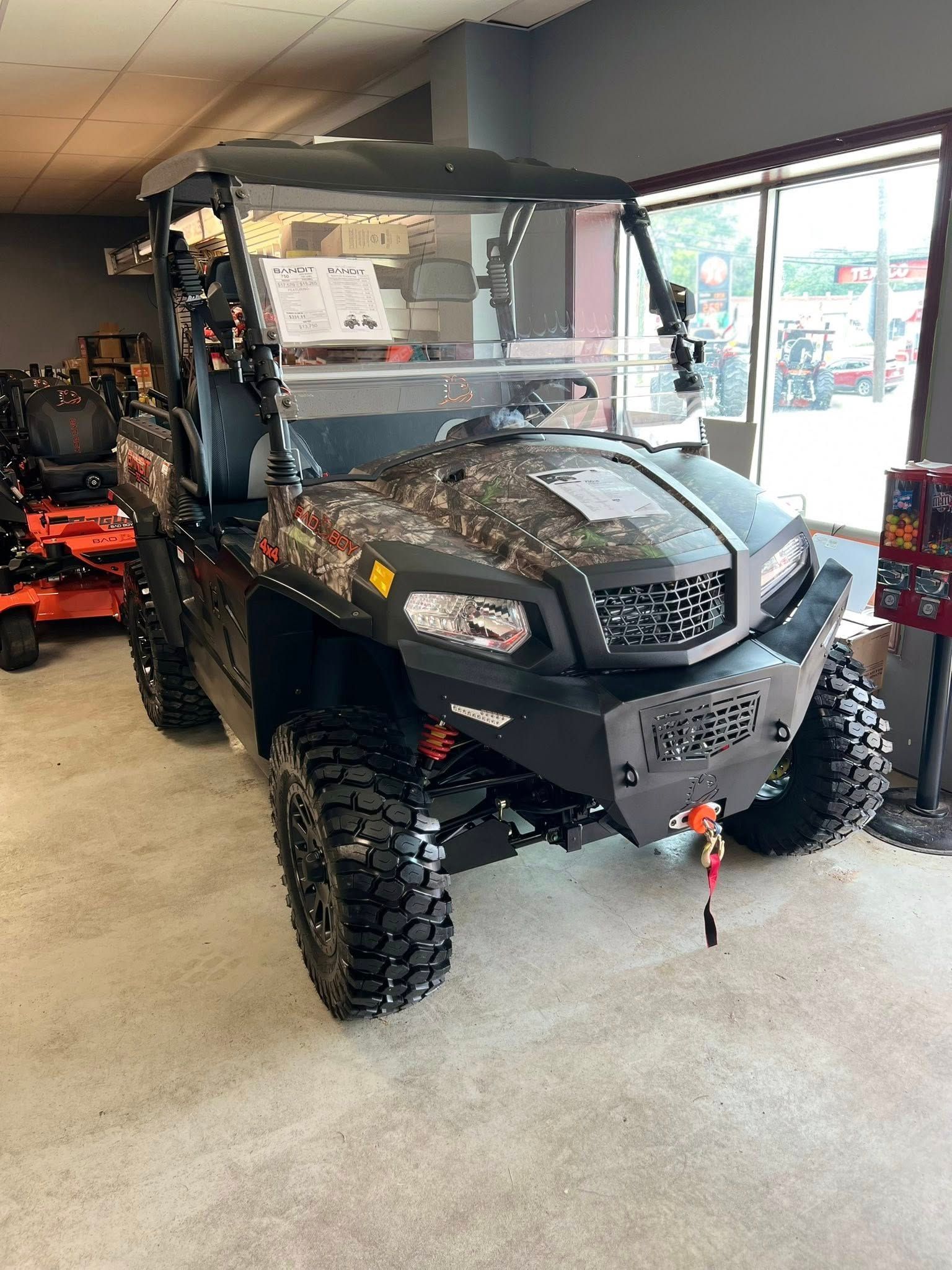Black off-road UTV with winch displayed in a showroom near large windows.