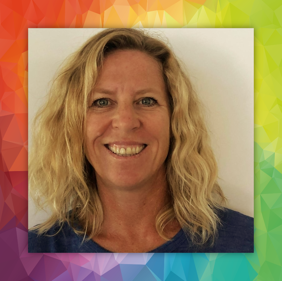 A woman with blonde hair is smiling in front of a colorful background