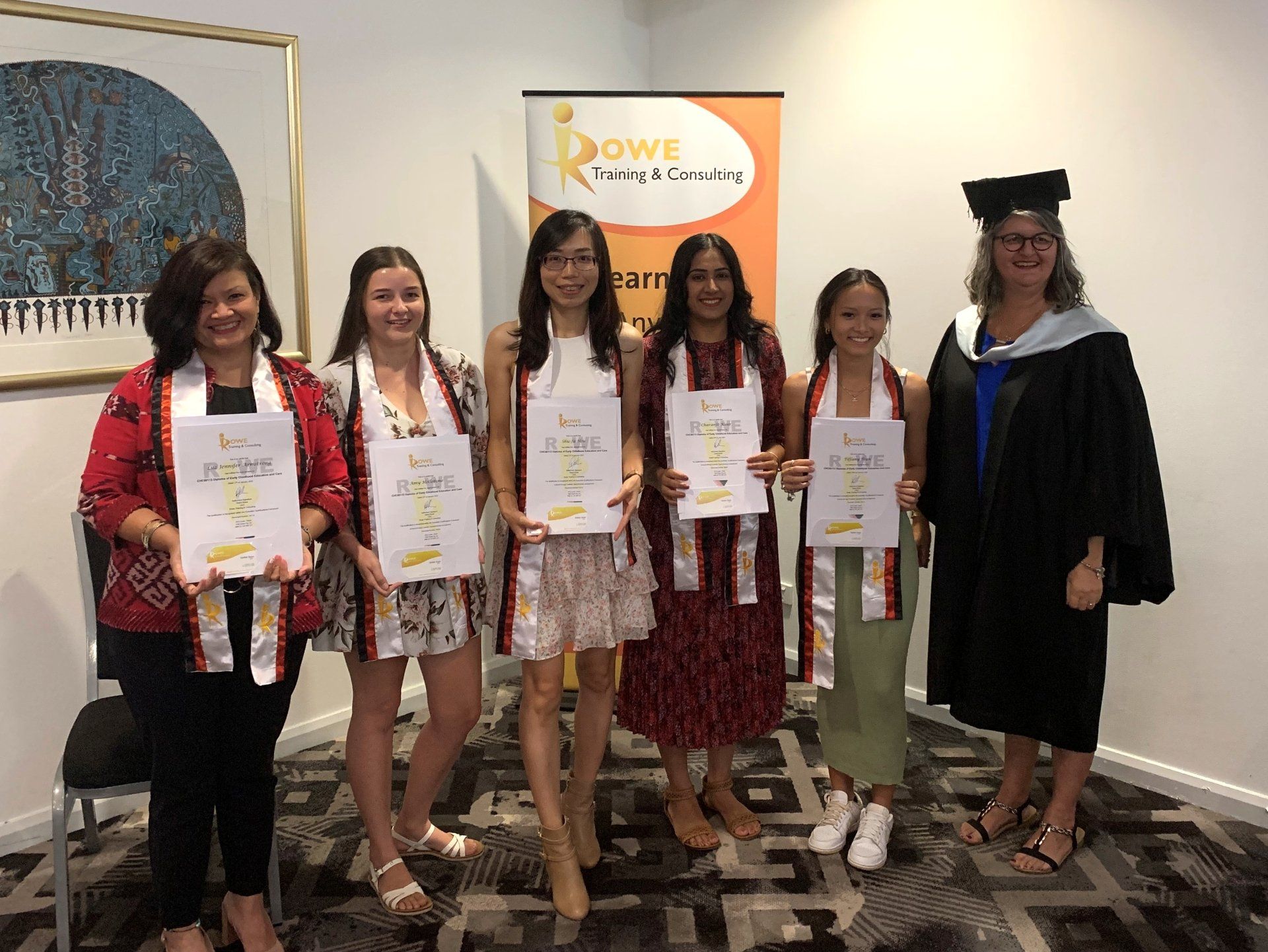 A group of women are standing next to each other in a room holding certificates.