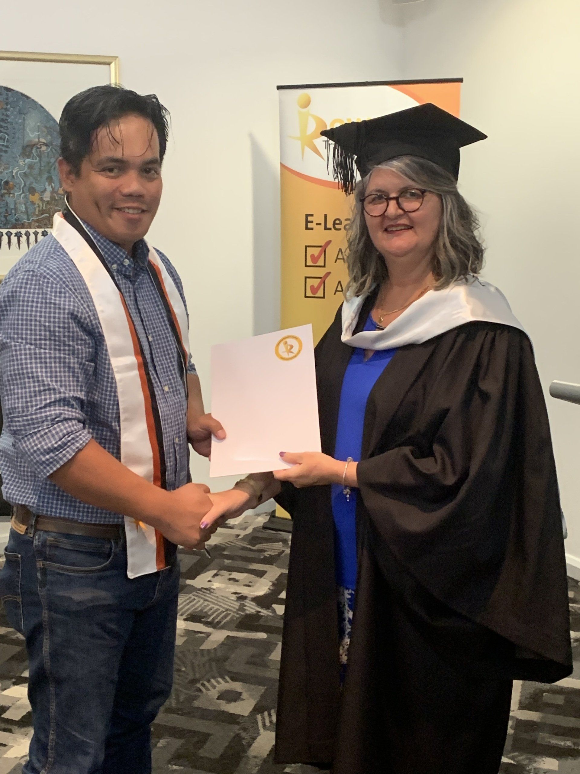 A man in a graduation cap and gown is shaking hands with a woman