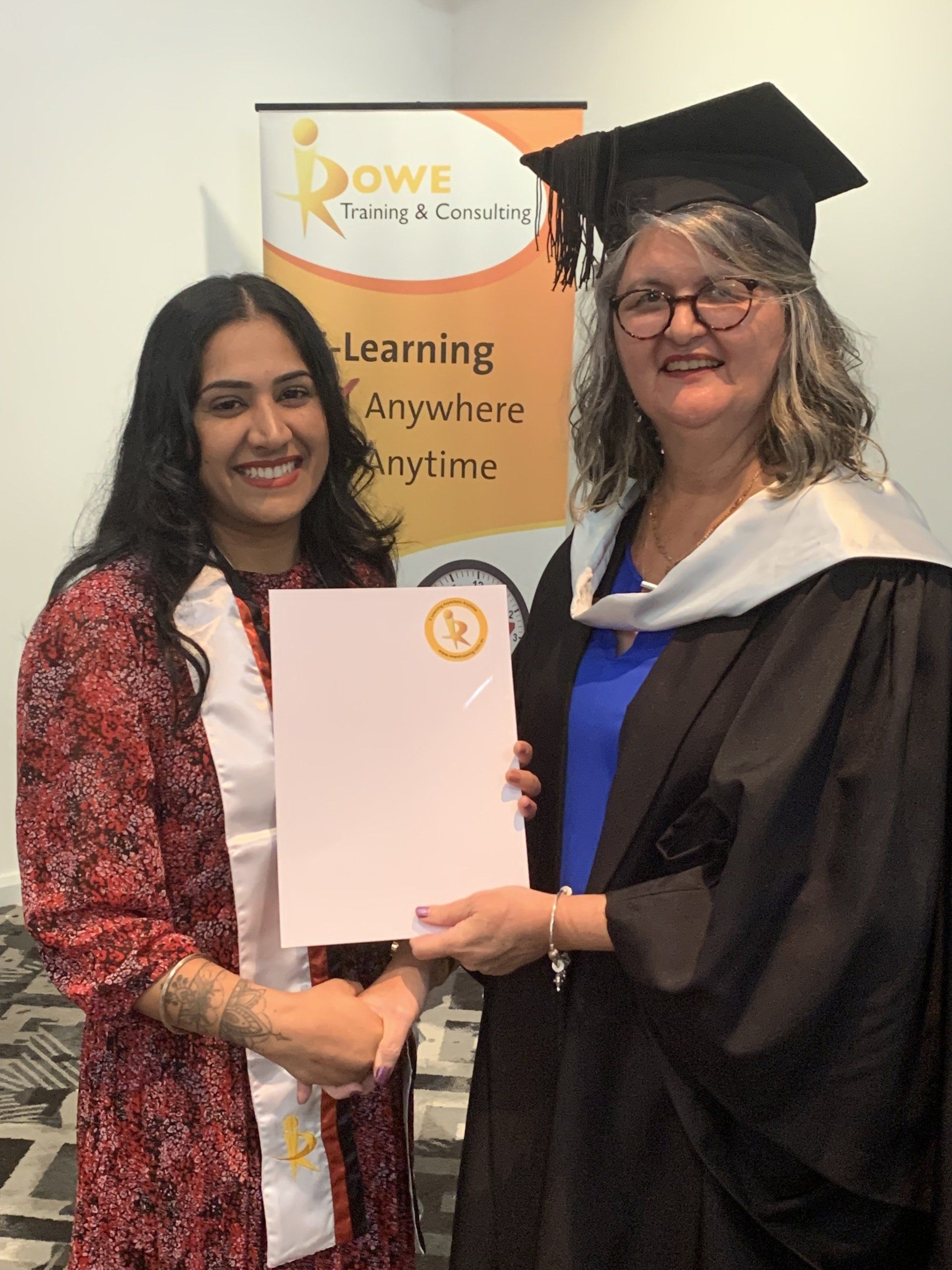 A woman in a graduation cap and gown is holding a certificate