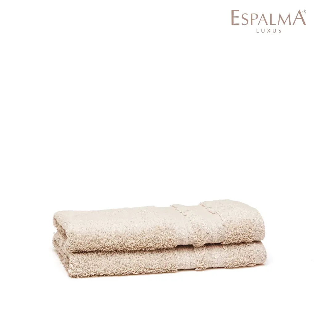 Dos toallas beige dobladas, apiladas una encima de la otra. Logotipo de ESPALMA LUXUS en la esquina superior derecha.