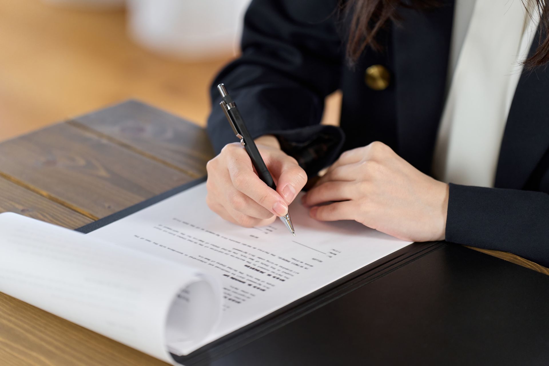 Person signing a document at a desk with a pen