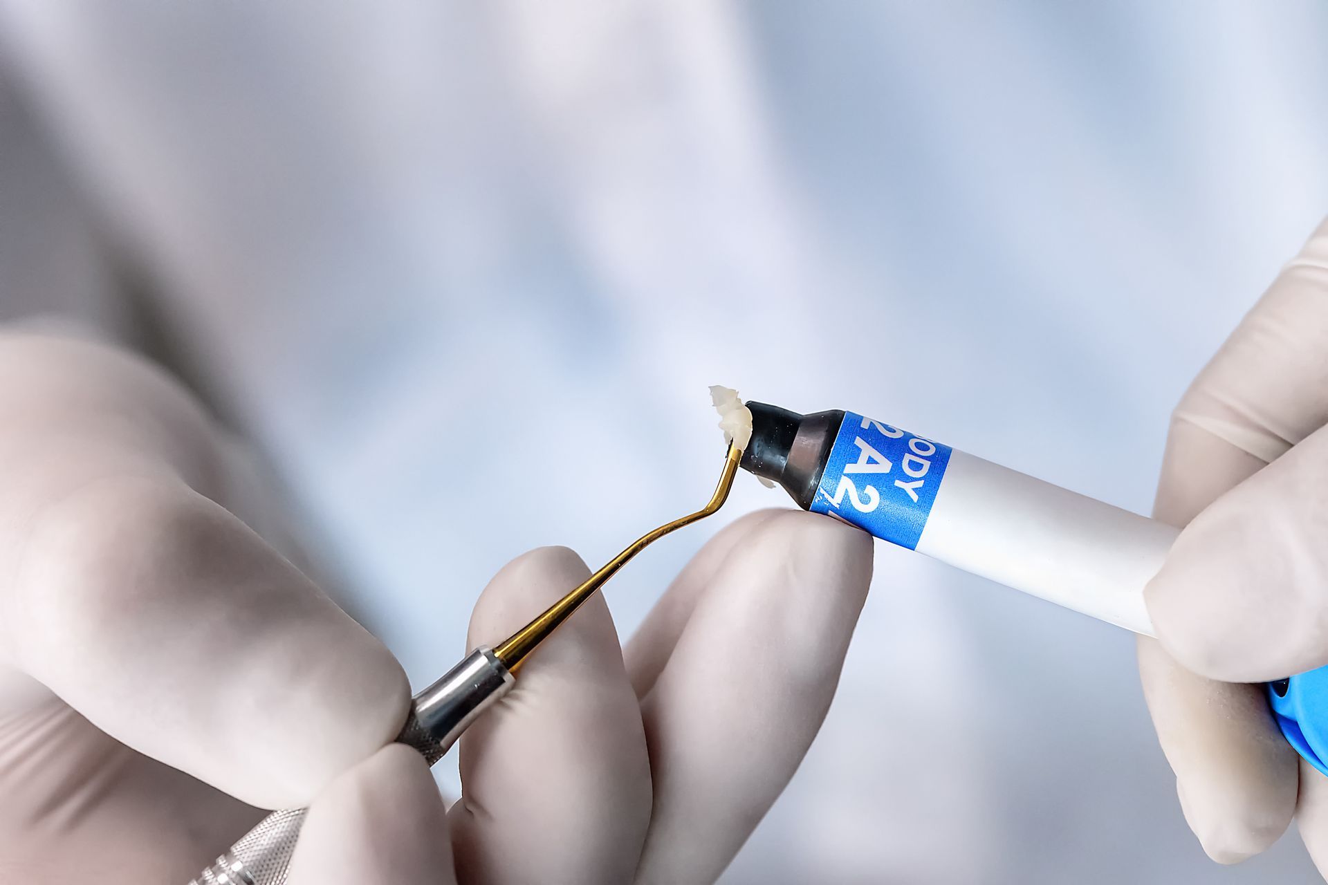 Gloved hands holding a dental drill and tool near a white dental impression mold Gloved hands holding a dental drill and tool near a white dental impression mold