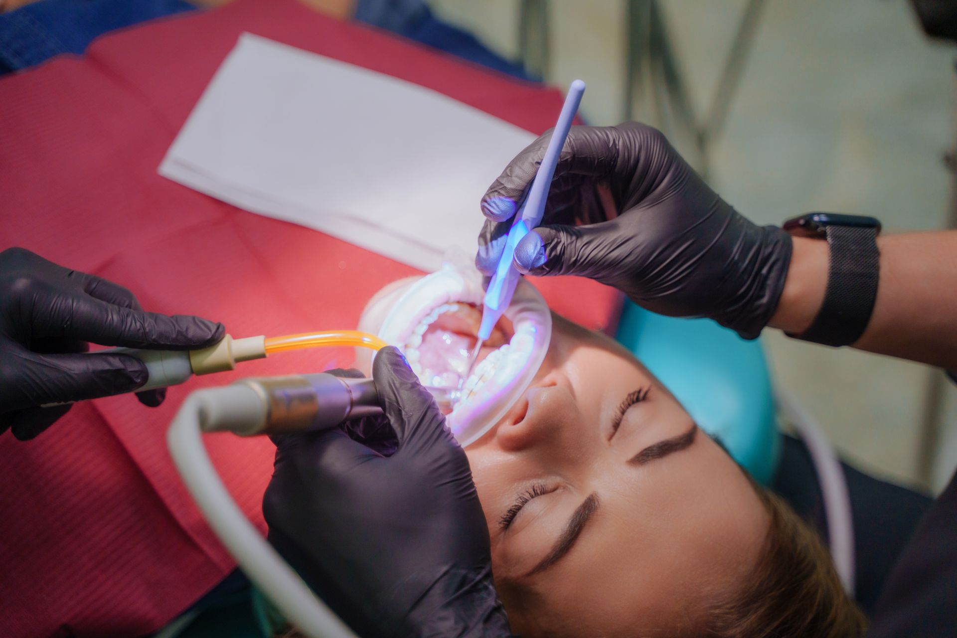Dental cleaning being performed on a patient in a chair, with gloved hands and dental tools.