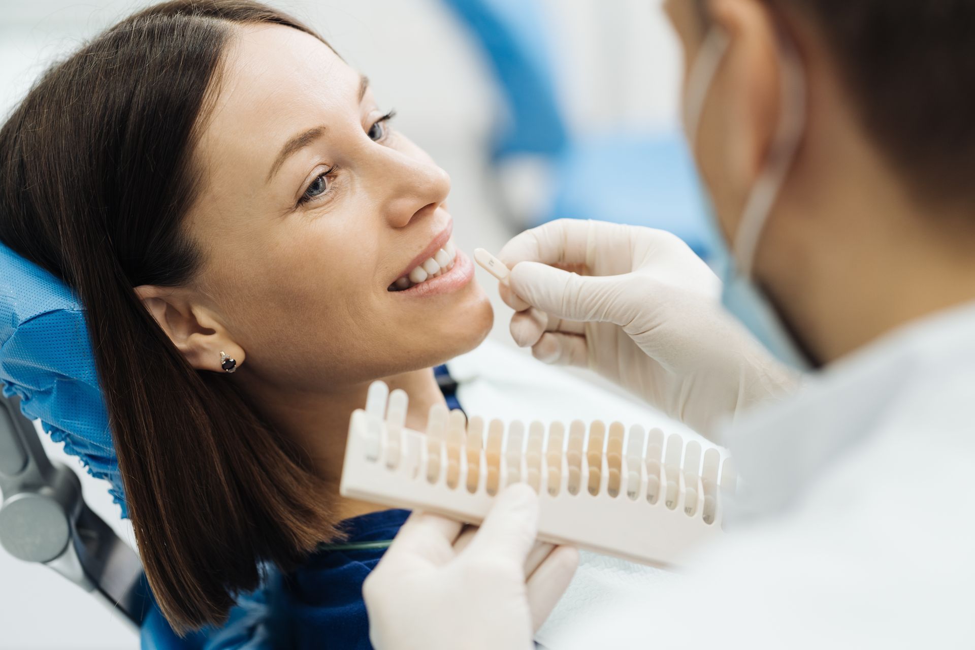 Dentist examining a smiling patient’s teeth in a bright clinic