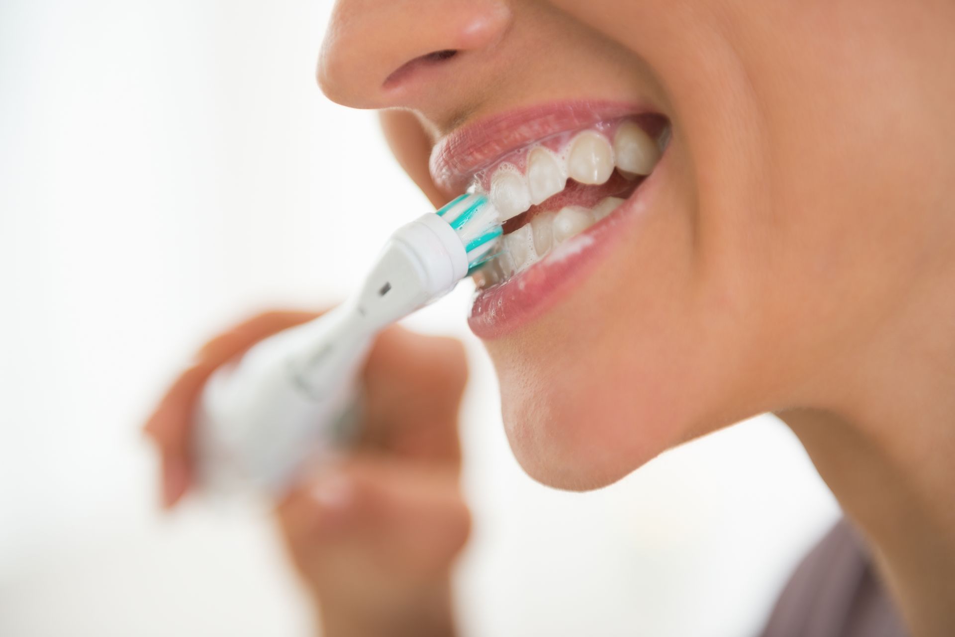 Person brushing teeth with an electric toothbrush, foam visible near the mouth