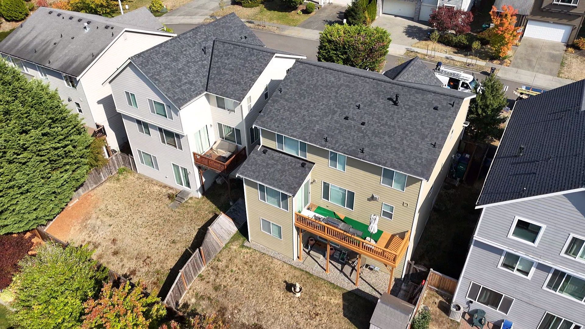 Aerial view of suburban houses with gray roofs and a tan home under construction in the center