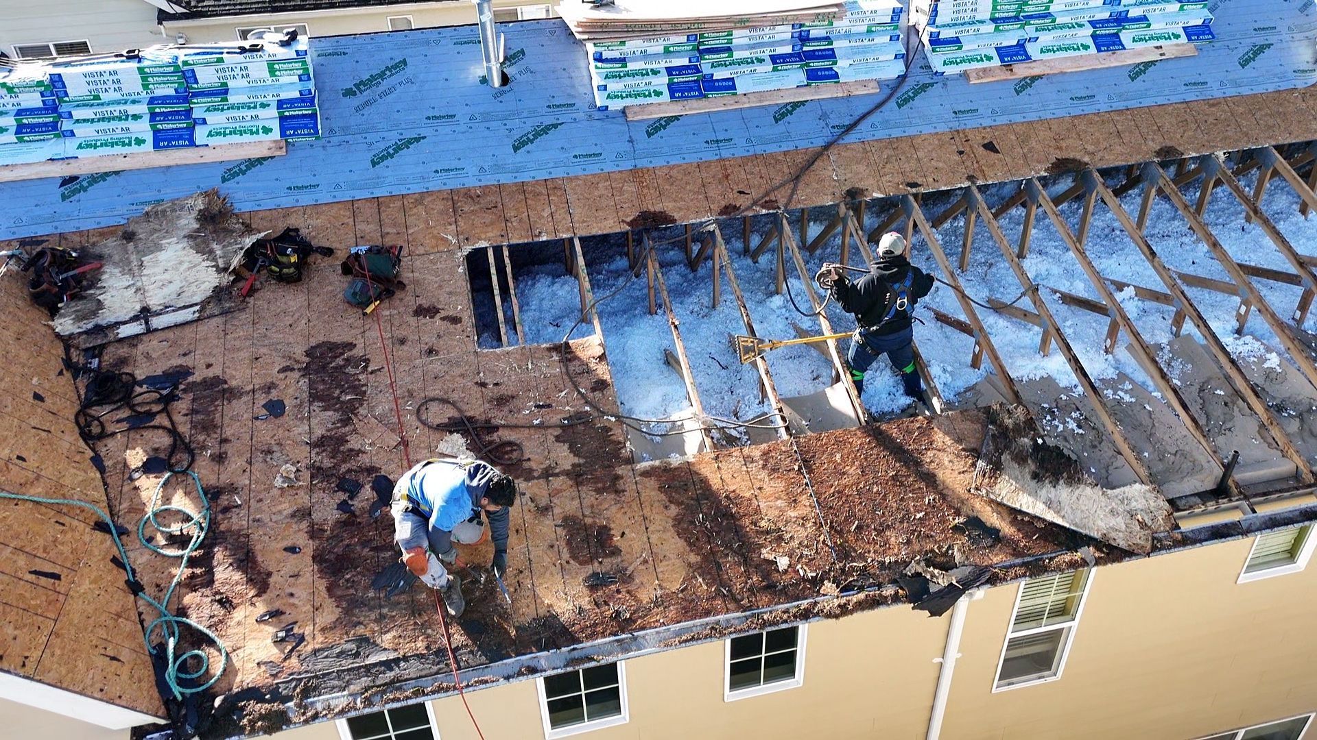 Damaged roof with burned sections and exposed framing on a beige building
