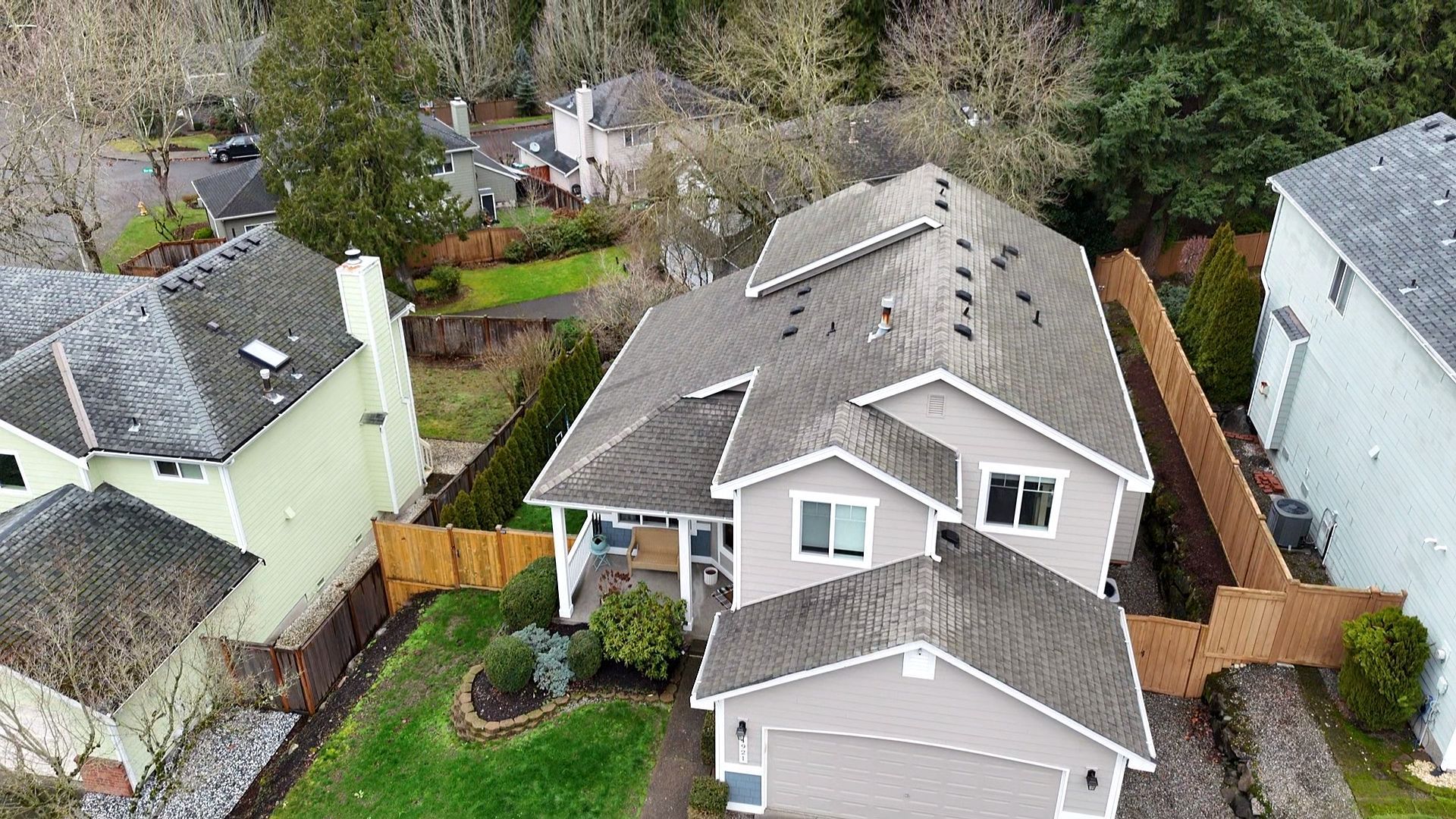Aerial view of a gray house with a fenced yard and neighboring homes in a suburban neighborhood