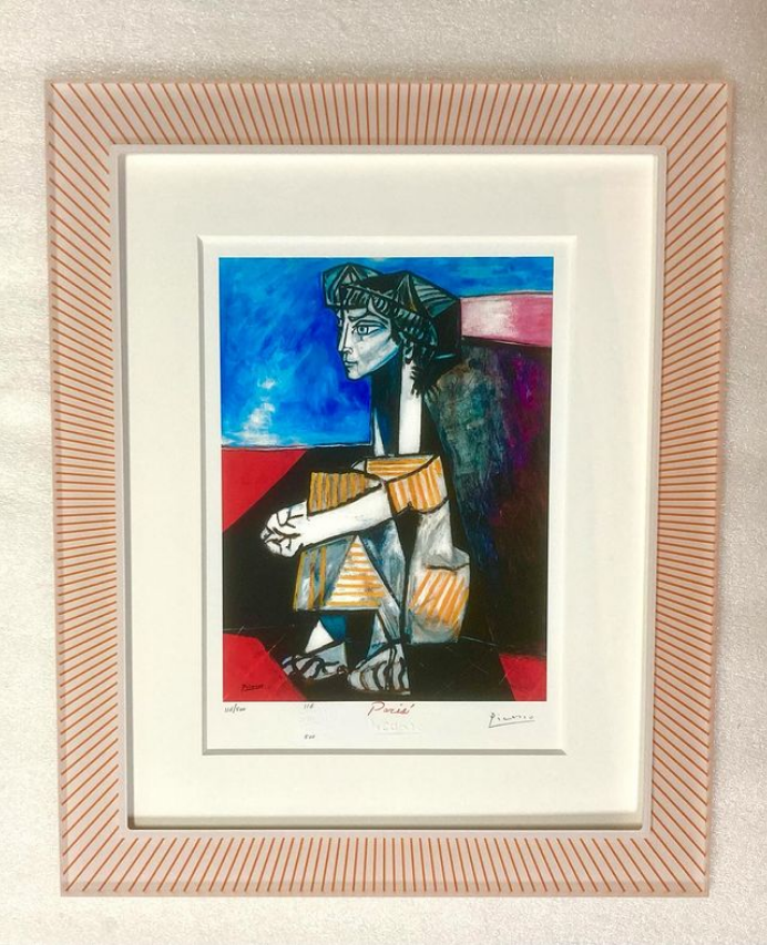 A framed painting of a woman sitting in a chair