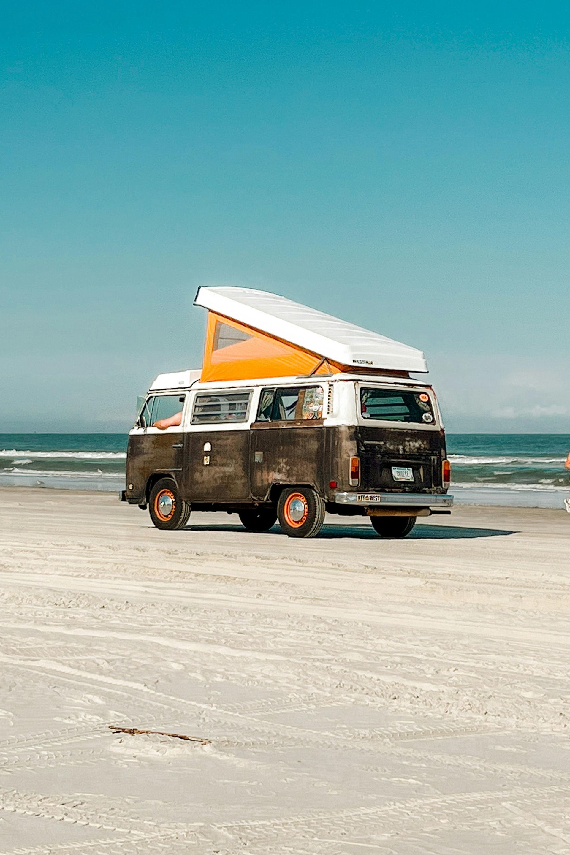 A camper van is driving down a hill on a sunny day.