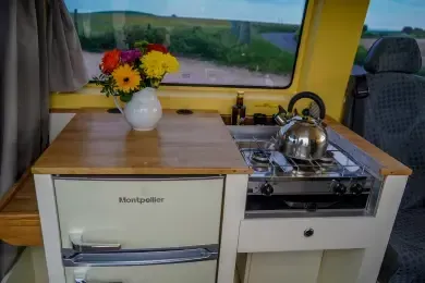 A kitchen in a van with a vase of flowers on the counter.
