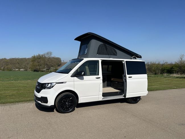 A white van with a black top is parked on the side of the road.